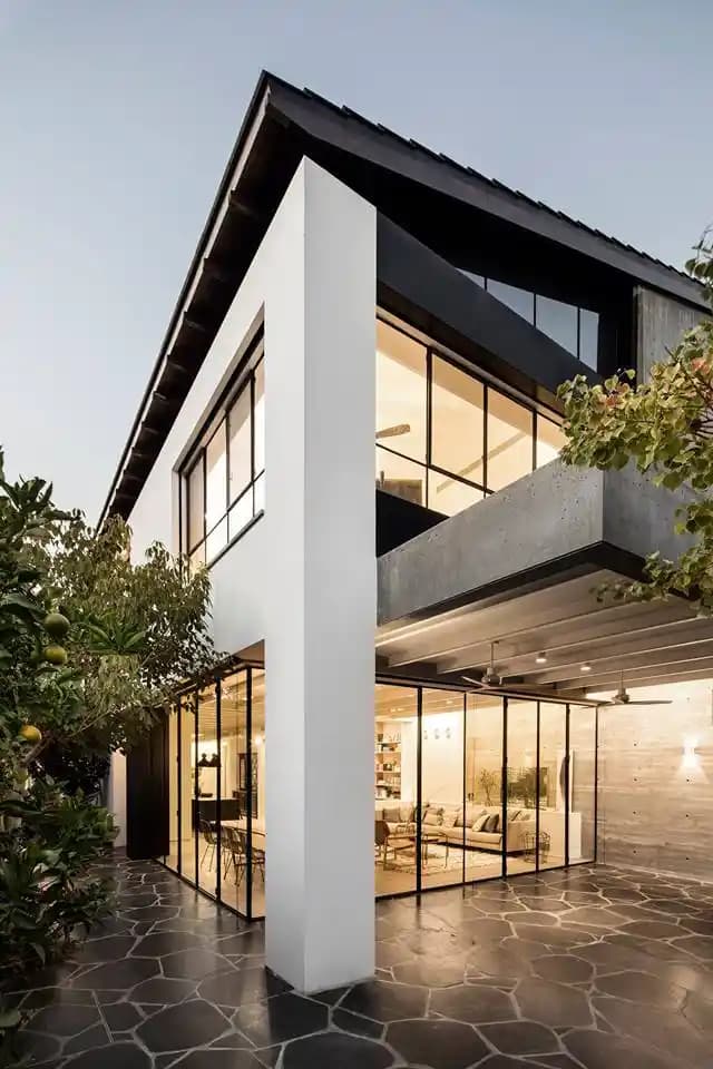 בית פרטי יוקרתי בשעות הערב עם תאורה חמה ומרפסות זכוכית