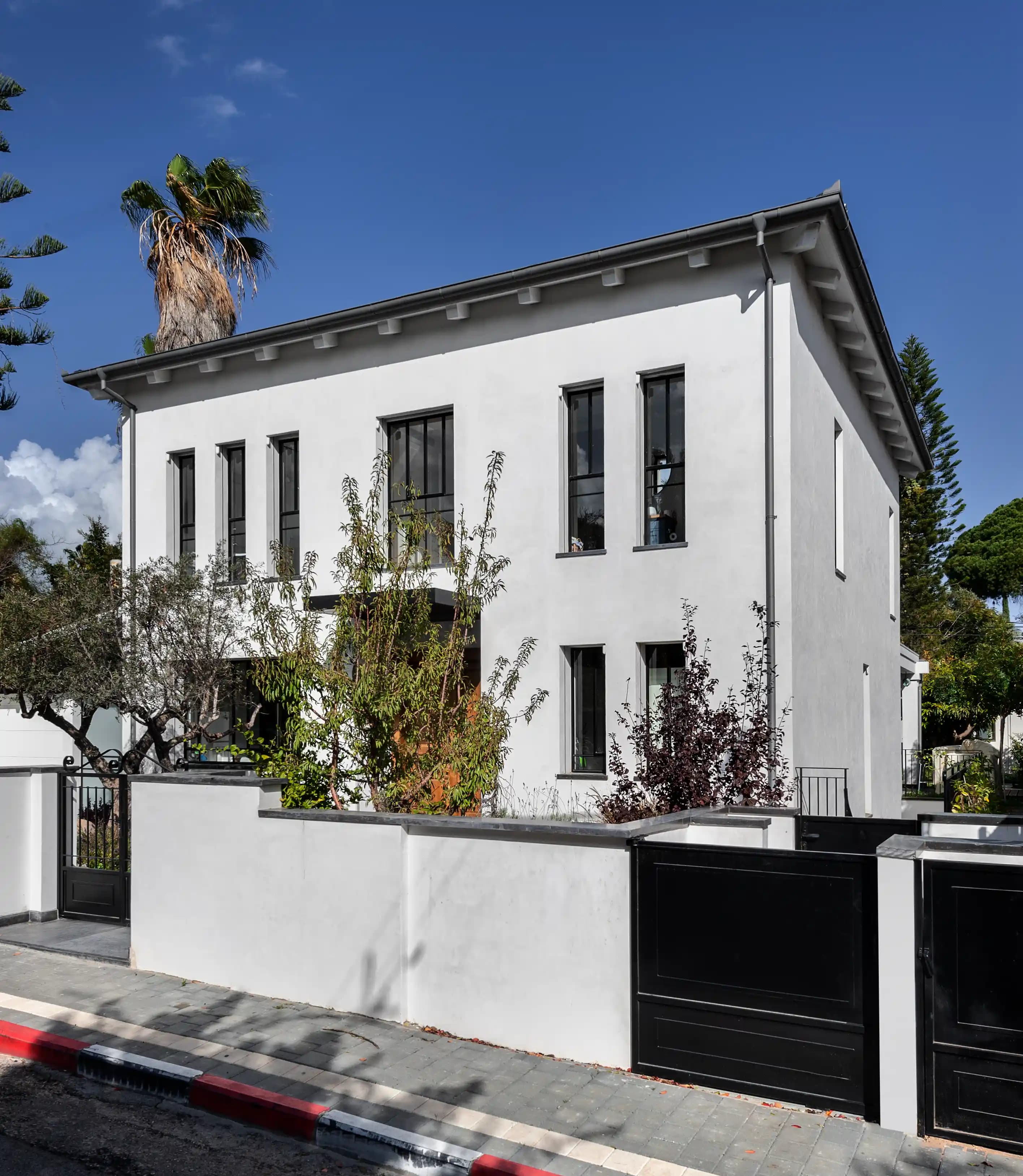 בית לבן דו קומתי עם חלונות גבוהים ושער כניסה מעוצב