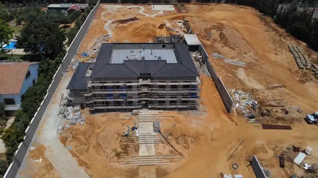 מבט אווירי על אתר בנייה - בית בשלב שלד עם פיגומים